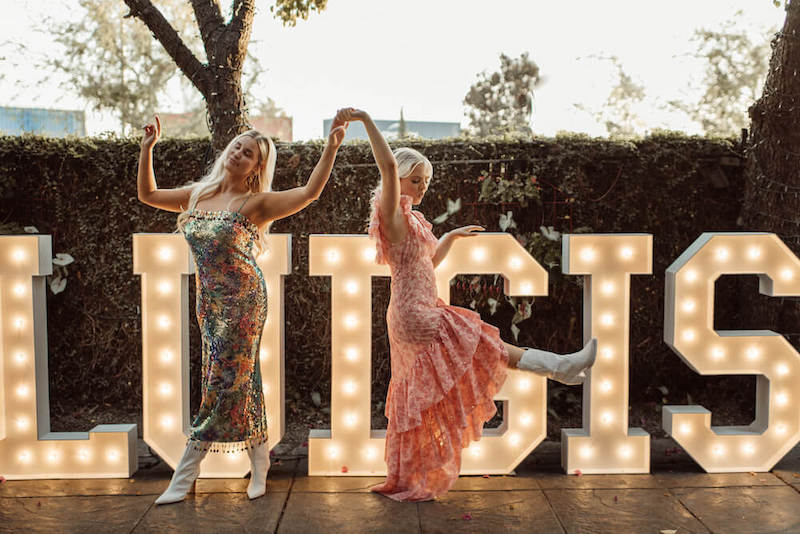 Women dancing in front of a "Luigis" light sign