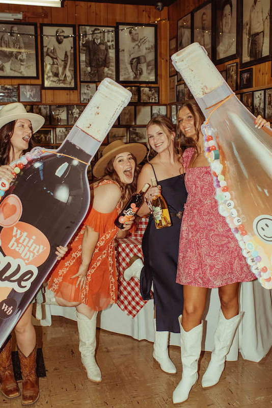 girls posing with giant wine bottles